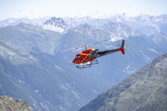 Red helicopter flying in the mountains, Stubai Alps, South Tyrol, Italy