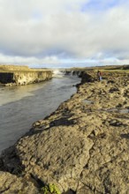 Hikers at the river Jökulsa a Fjöllum, canyon, waterfall Selfoss on the horizon, North Iceland,