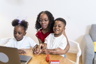 Mother and children using laptop for online education, homeschooling, working from home or watching