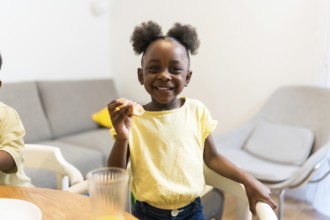 Smiling young girl savoring a delicious sweet treat while sitting at the dining room table,