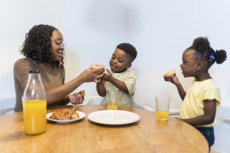 Happy family sharing a joyful breakfast at home, savoring delicious donuts and refreshing juice