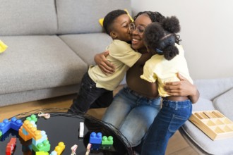 Loving mother enjoying a tender moment with her kids, receiving hugs and kisses in their cozy