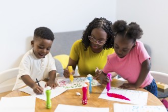 Mother and her two children are engaging in a creative painting activity at home, using colorful