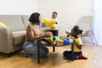 Happy family playing together at home, enjoying quality time with building blocks and pillows in a
