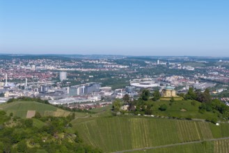 Vineyards and green hill with a building, city panorama in the background, view of the burial