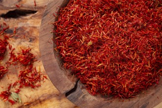Spice saffron threads, in a wooden bowl, on a wooden table, top view, close-up