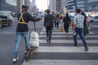 Man crossing a pedestrian crossing on an electric scooter, Abu Dhabi, United Arab Emirates