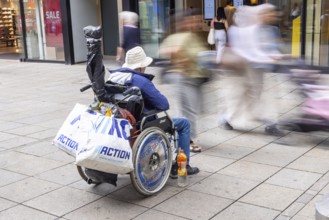 A man in a wheelchair in the Königstraße pedestrian zone in front of a branch of the McDonald's