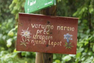 Sign with Slovenian text in front of a green, natural backdrop, Zgornje Jezersko, Gorenjska,