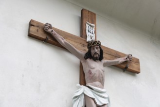 Wooden cross with a depiction of Jesus mounted on a white wall, Zgornje Jezersko, Gorenjska,