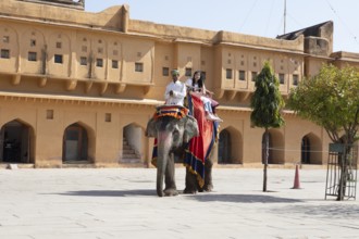 Indian mahout and Indian woman riding a colourfully painted elephant at the Amber Fort or fortress,