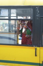 Colourfully dressed Indian woman in a yellow bus in the old city, Jaipur, Rajasthan, India
