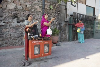 Indian woman holding tea lights in the air at a fire hydrant, Govind Dev Ji Hindu temple in the old