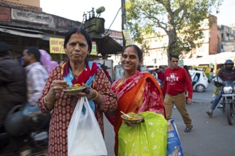 Indian woman eating kachori or dumplings filled with beans in the old city centre, Jaipur,