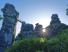 The morning sun shines through an opening in the Externsteine. The Externsteine, a sandstone rock