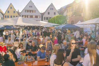 People enjoying a town festival on a market square, surrounded by historic buildings in the