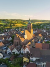 Historic church in the middle of a town with hills in the background in warm evening light, 950