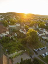 Landscape with a village car park at sunset, surrounded by trees and a quiet atmosphere, 950 years