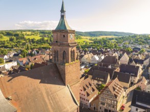 Church tower overlooks a hilly, rural landscape and a village with half-timbered houses, 950 years