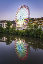 Rainbow-coloured Ferris wheel at night, illuminated, with reflection in the water, Calw, Germany