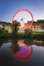 Red and blue Ferris wheel at night, its lights reflected in the water, Calw, Germany