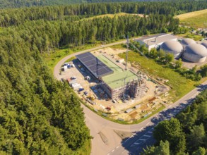 Industrial area in the middle of a forest with solar panels and construction crane, bird's eye