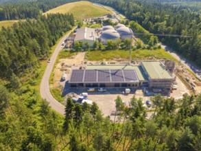 Construction work in a rural setting with solar energy on the roofs and surrounded by forest, new