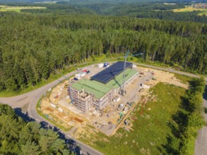 Building complex in a wooded landscape with solar panels on the roof and a crane, new fire station,