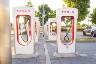Tesla charging stations in a sunny environment with green trees in the background, Tesla