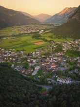 View over a town in the valley, surrounded by mountains and soft evening light
