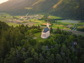 Church above a valley with a village surrounded by mountains at dusk