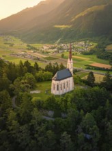 Church in the evening light, embedded in a mountainous landscape with a wide valley
