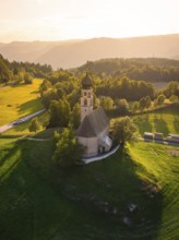 Idyllic church on a hill surrounded by green countryside and warm sunset light
