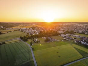 Aerial view of a village at sunset, surrounded by fields and trees, gentle atmosphere, Renningen,