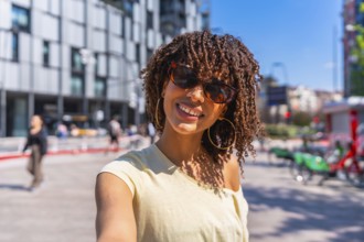 Smiling tourist enjoying a sunny day in the city, capturing the moment with a selfie while soaking