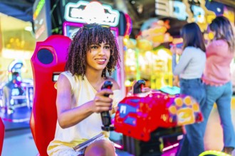 Young woman having fun playing a racing simulator in an amusement arcade with her friends in the