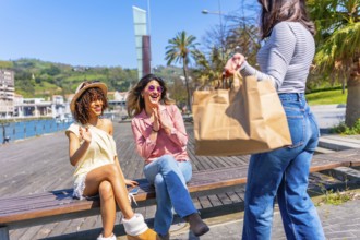 Three happy women enjoying sunny day in a city with palm trees and waterfront view, having fun