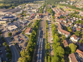 Metropolitan scene with railway tracks and factories, diverse buildings in summery surroundings,