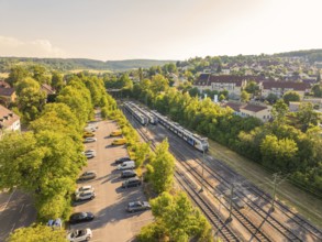 Train and cars in a green environment next to a housing estate, bright summer atmosphere, Weil der
