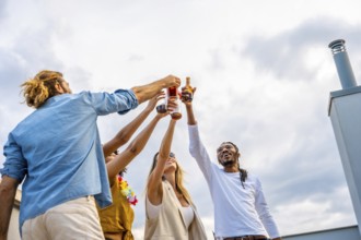 Happy multi ethnic friends raising their glasses for a celebratory toast, enjoying a rooftop party