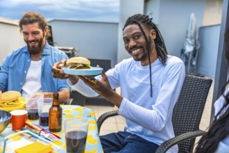 Cheerful friends enjoying a rooftop barbecue party, sharing burgers, drinks, and laughter on a