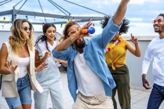 Diverse group of friends celebrating on a vibrant rooftop, singing and dancing joyfully together,
