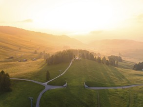 Wide, green hills under bright evening light with scattered mountain huts, Alpe di Siusi,
