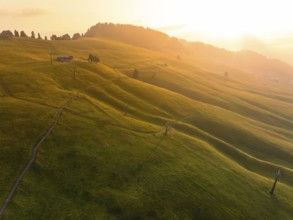 Green, gentle hills in warm light with paths and a secluded building, Alpe di Siusi, Dolomites,