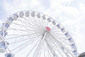 Modern Ferris wheel with gondolas in front of a slightly cloudy sky, Ferris wheel construction,