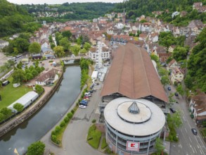Hilly village with a large building and Ferris wheel on the river, construction of Ferris wheel,