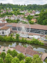 Ferris wheel next to modern and historic buildings in a green setting, Ferris wheel construction,