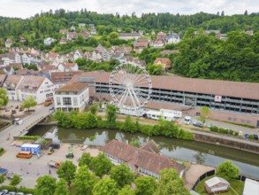 Ferris wheel next to a river and buildings in a green village, Ferris wheel construction, Calw,