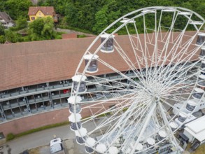 Close-up of the Ferris wheel with detailed view of the cabins and buildings in the background,