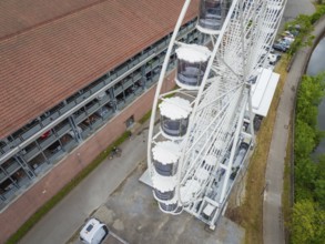 Detailed view of the Ferris wheel cabins next to a road and building, Ferris wheel construction,